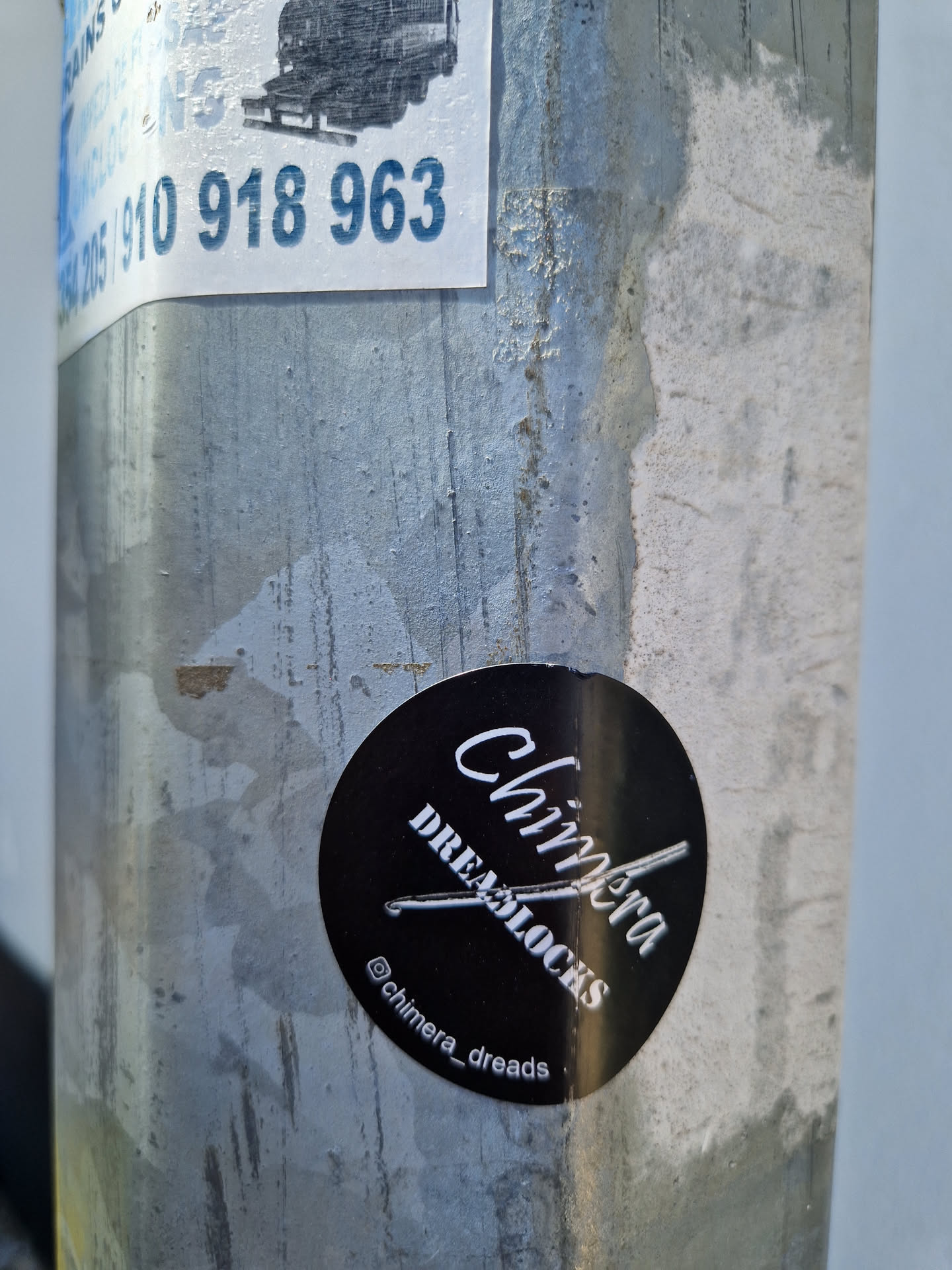 A black and white round sticker with the text "Chimera Dreamlocks" and the Instagram handle @chimera_dreads. The sticker is applied to a weathered metal pole.