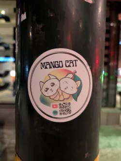 Sticker featuring two cute cartoon cats nestled together, resembling a mango. The sticker includes social media links to YouTube and Spotify, along with a QR code.