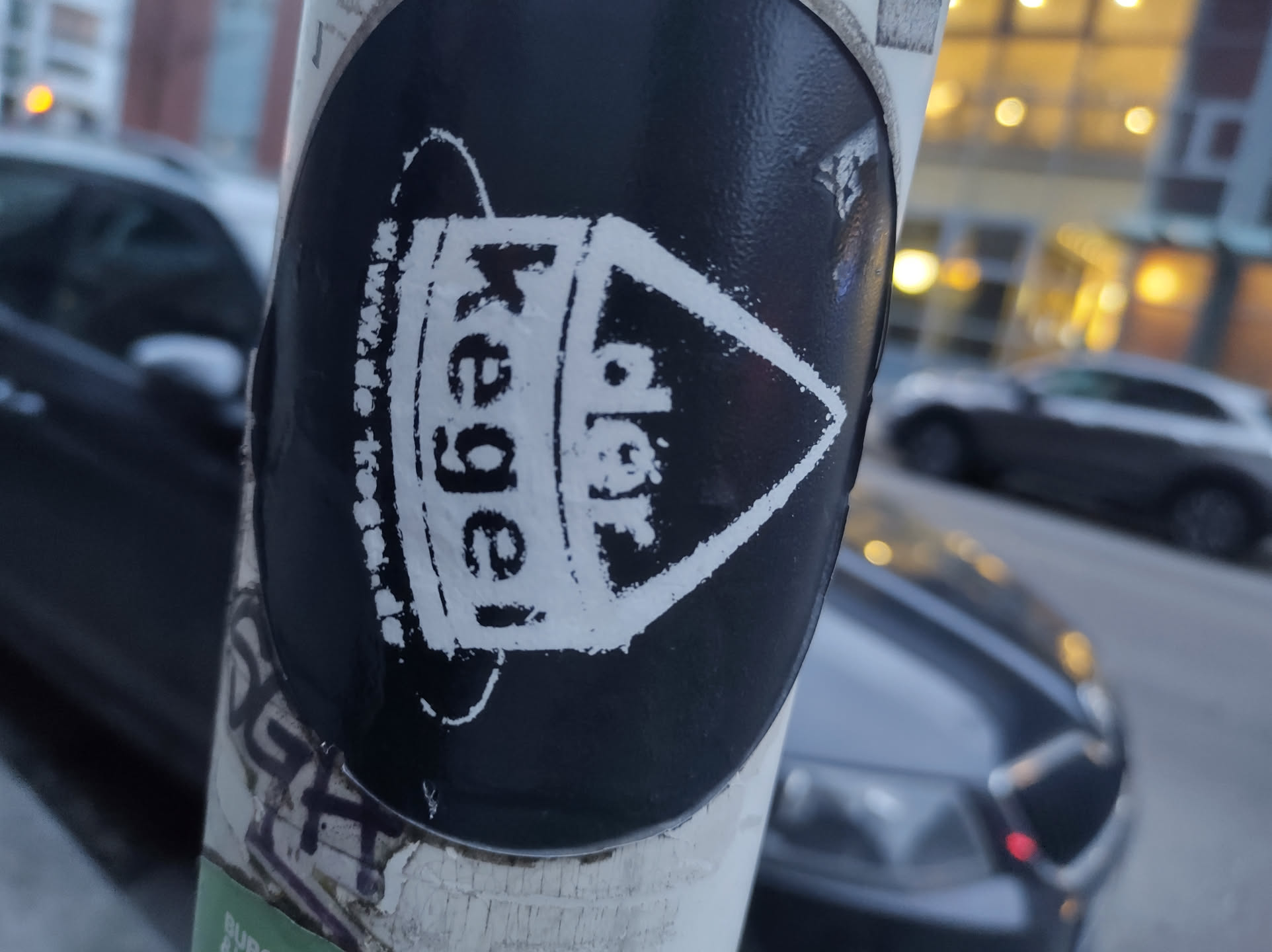 Black and white sticker with the word "Kegel" prominently displayed in a stylized font within a geometric shape resembling a spaceship or a pin.  The design has a slightly grungy, hand-made aesthetic.