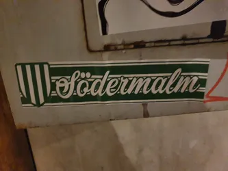 A green and white sticker with the word Södermalm written in a stylized script.  It features a vertical striped emblem on the left side.