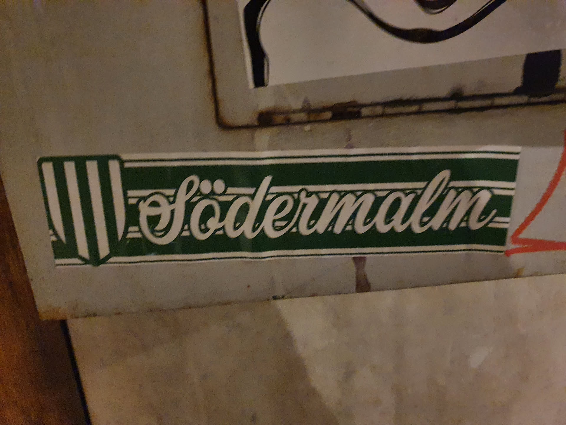 A green and white sticker with the word Södermalm written in a stylized script.  It features a vertical striped emblem on the left side.