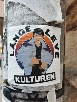 A sticker featuring an illustration of a man in a jacket, holding drinks. The text around him says  "Länge leve kulturen" which translates to "Long live culture" in Swedish. 