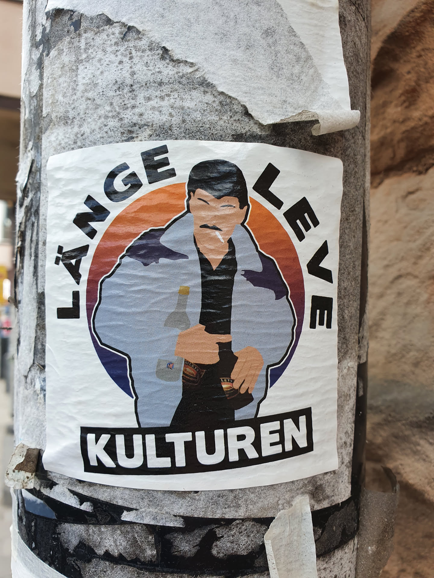 A sticker featuring an illustration of a man in a jacket, holding drinks. The text around him says  "Länge leve kulturen" which translates to "Long live culture" in Swedish. 