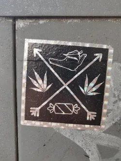 Holographic sticker featuring a shoe, cannabis leaves, candy, and arrows. The sticker has a dark background with a iridescent border. 