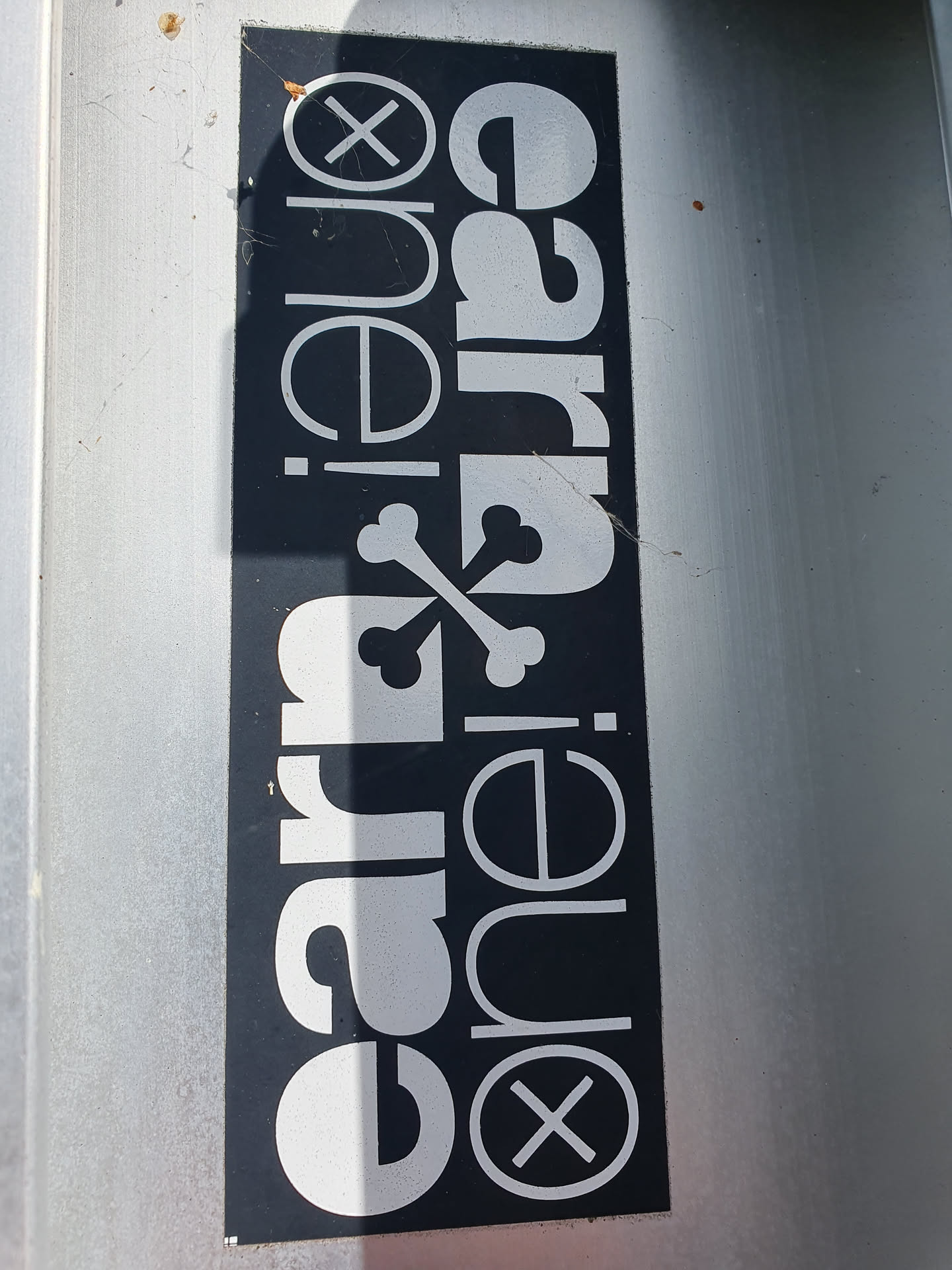 A black and white sticker with the text 'ear·one·carrie' arranged in a stylized design.  The text is surrounded by graphical elements, including an 'X' symbol.
