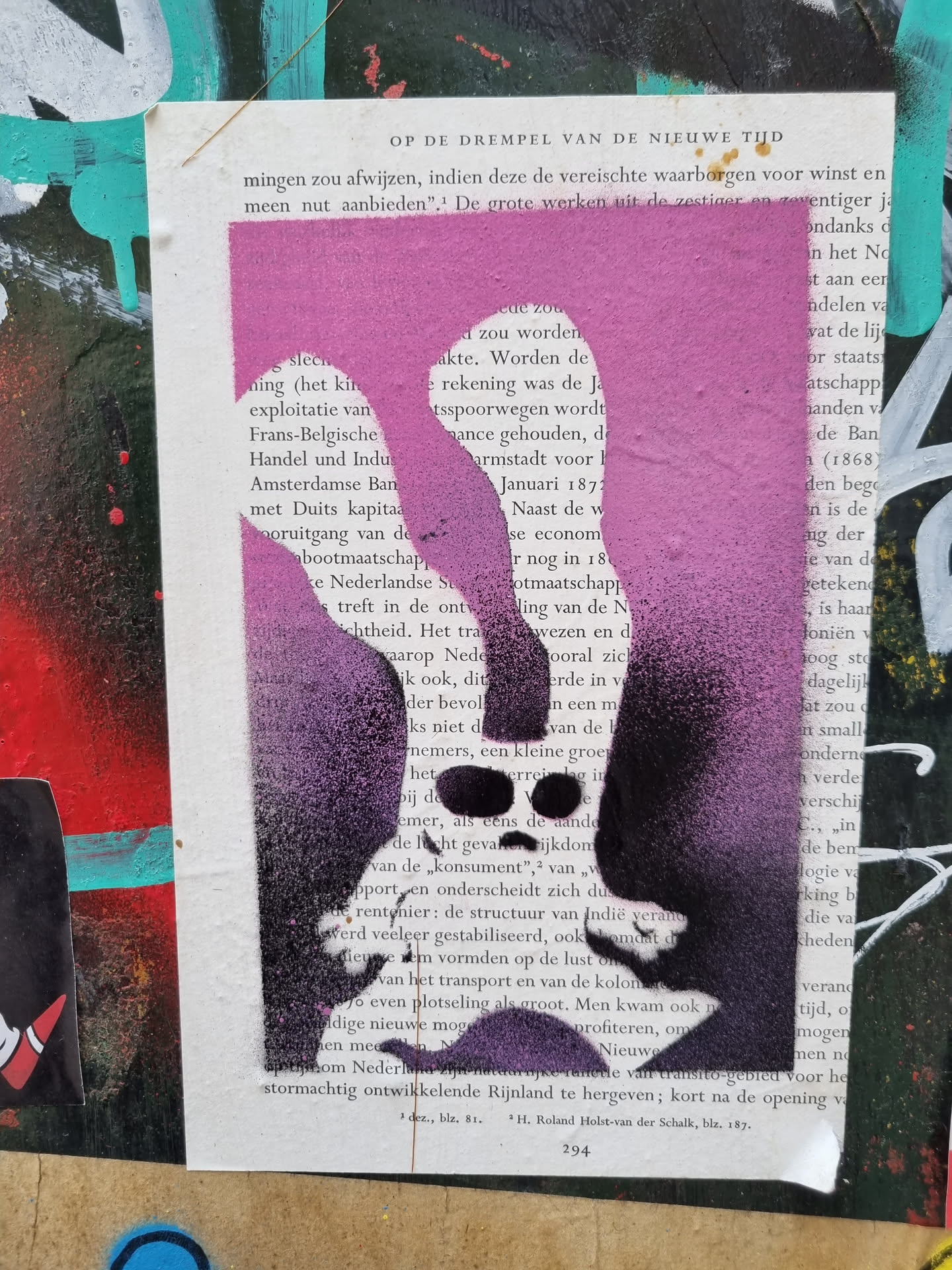 A purple and pink stencil graffiti of a face on a page of a book. The stencil is layered with different shades of purple and pink. The background is a page of a book with some text visible. The stencil is a simple design of a face with a nose, mouth and eyes.