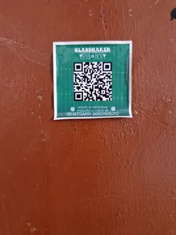Green sticker with a QR code, Instagram and Whatsapp contact information. 