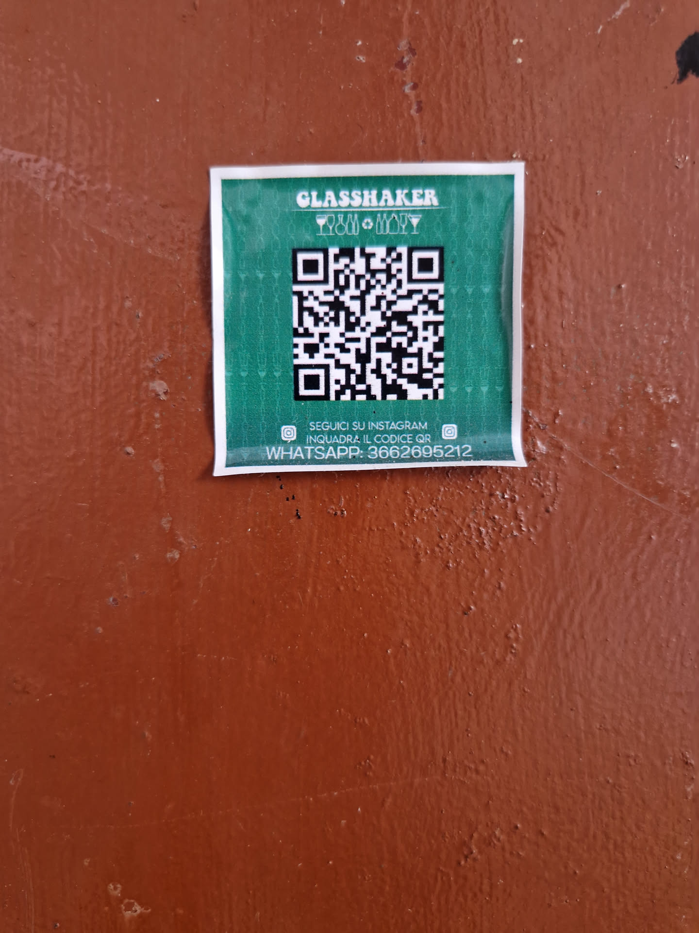 Green sticker with a QR code, Instagram and Whatsapp contact information. 