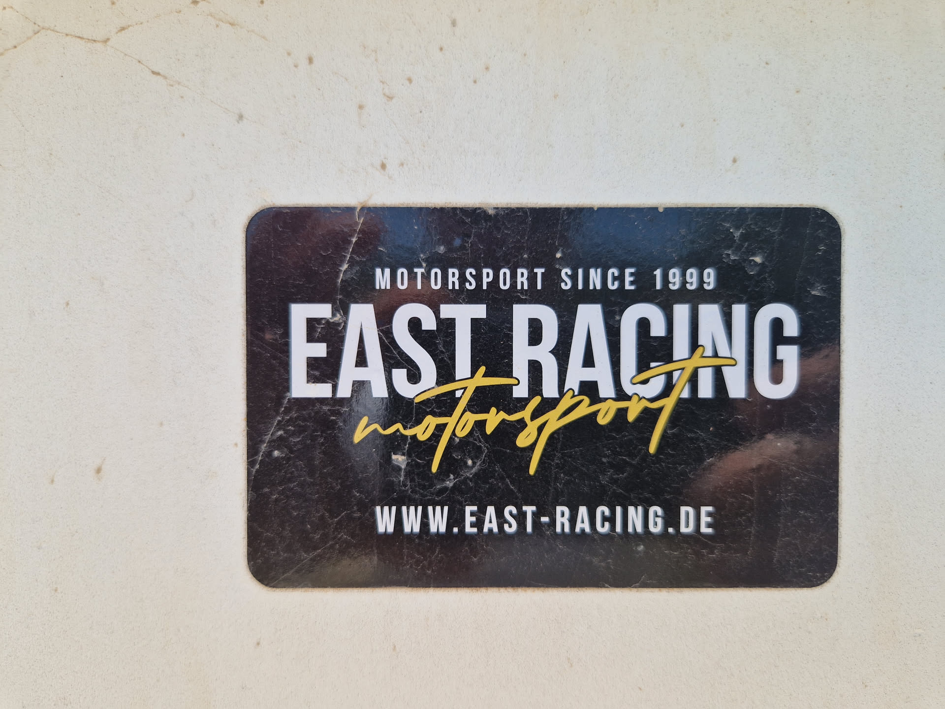 Black and gold sticker with the text East Racing and Motorsport. It also contains the website www.east-racing.de and the year 1999.