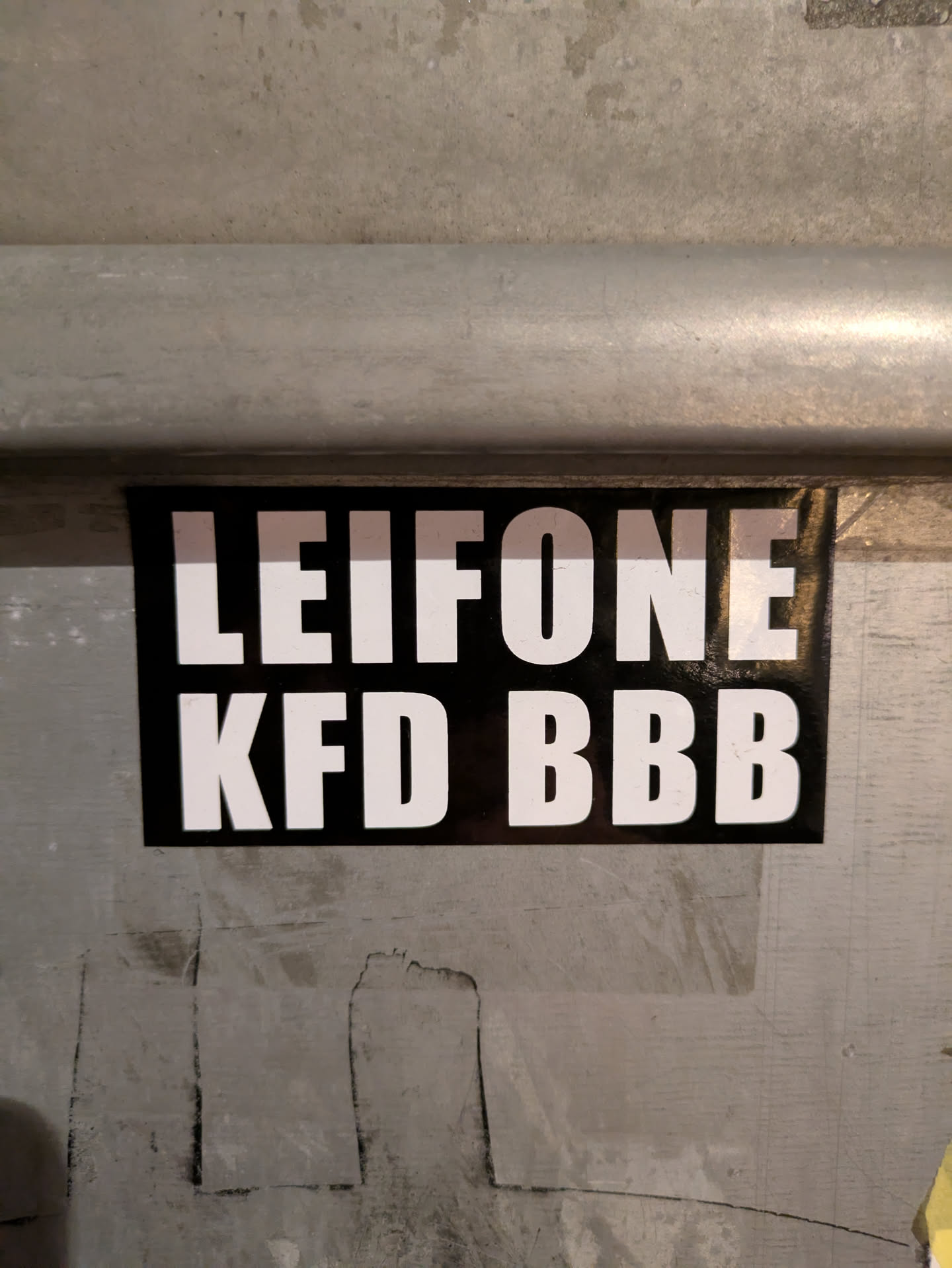 The sticker is rectangular with a black background and white text. The text is LEIFONE on the top line and KFD BBB on the bottom line.