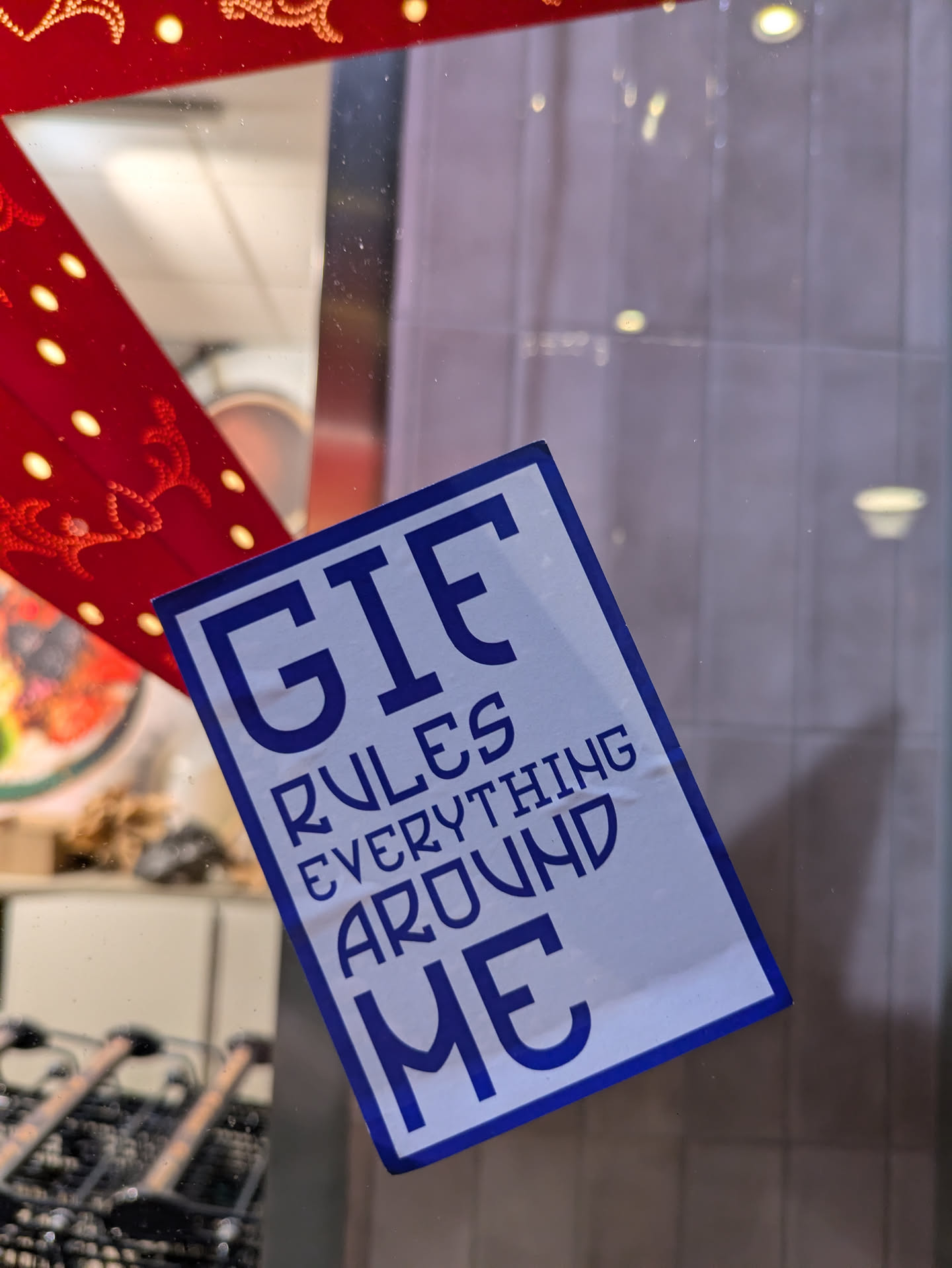 A white sticker with blue text. The text says GIEF rules everything around me.