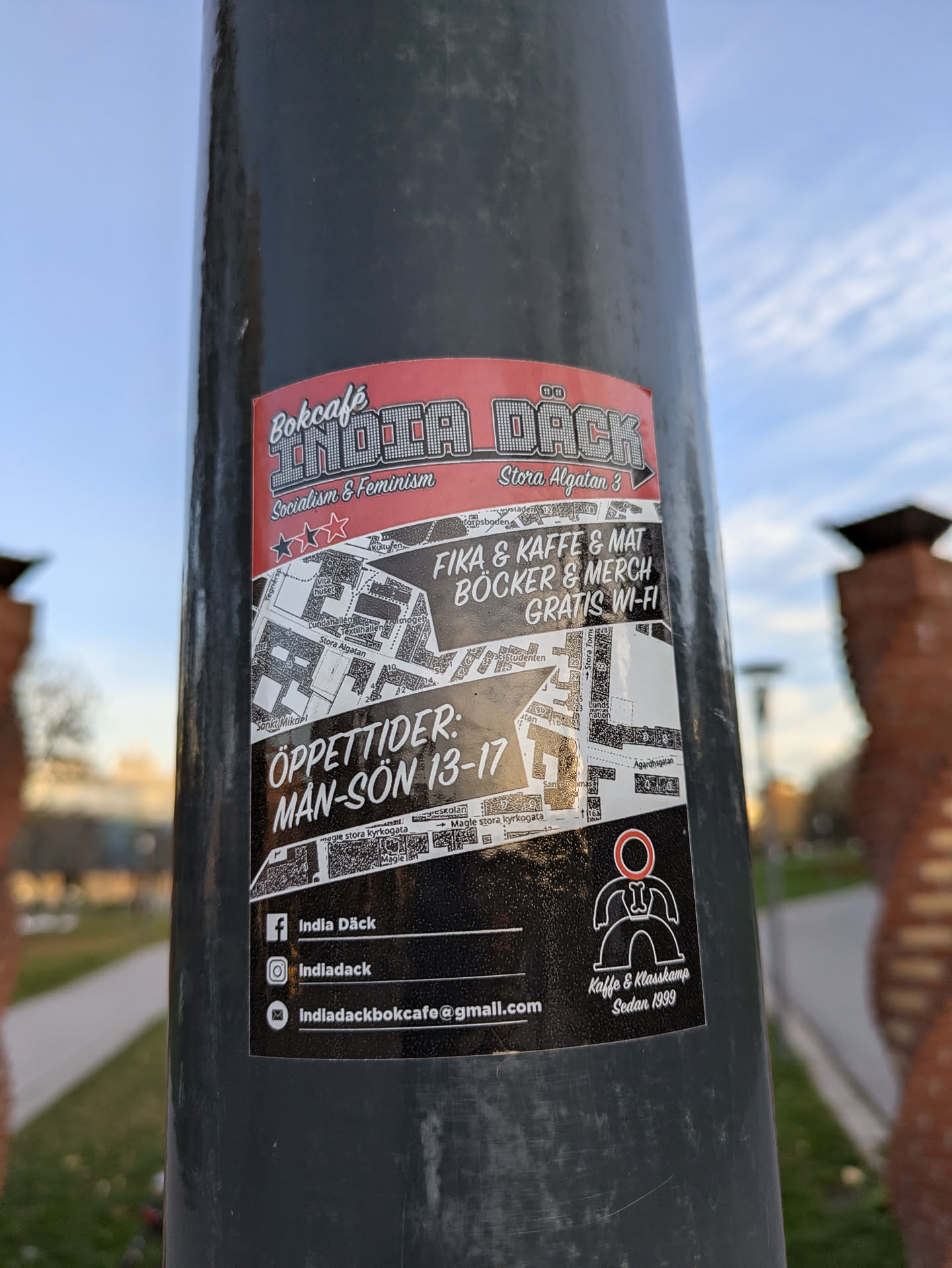 Sticker for Indie Däck, a bookcafe in Stockholm, Sweden. The sticker features a map, opening times, and social media information.  It's designed in black and red with a minimalist style.