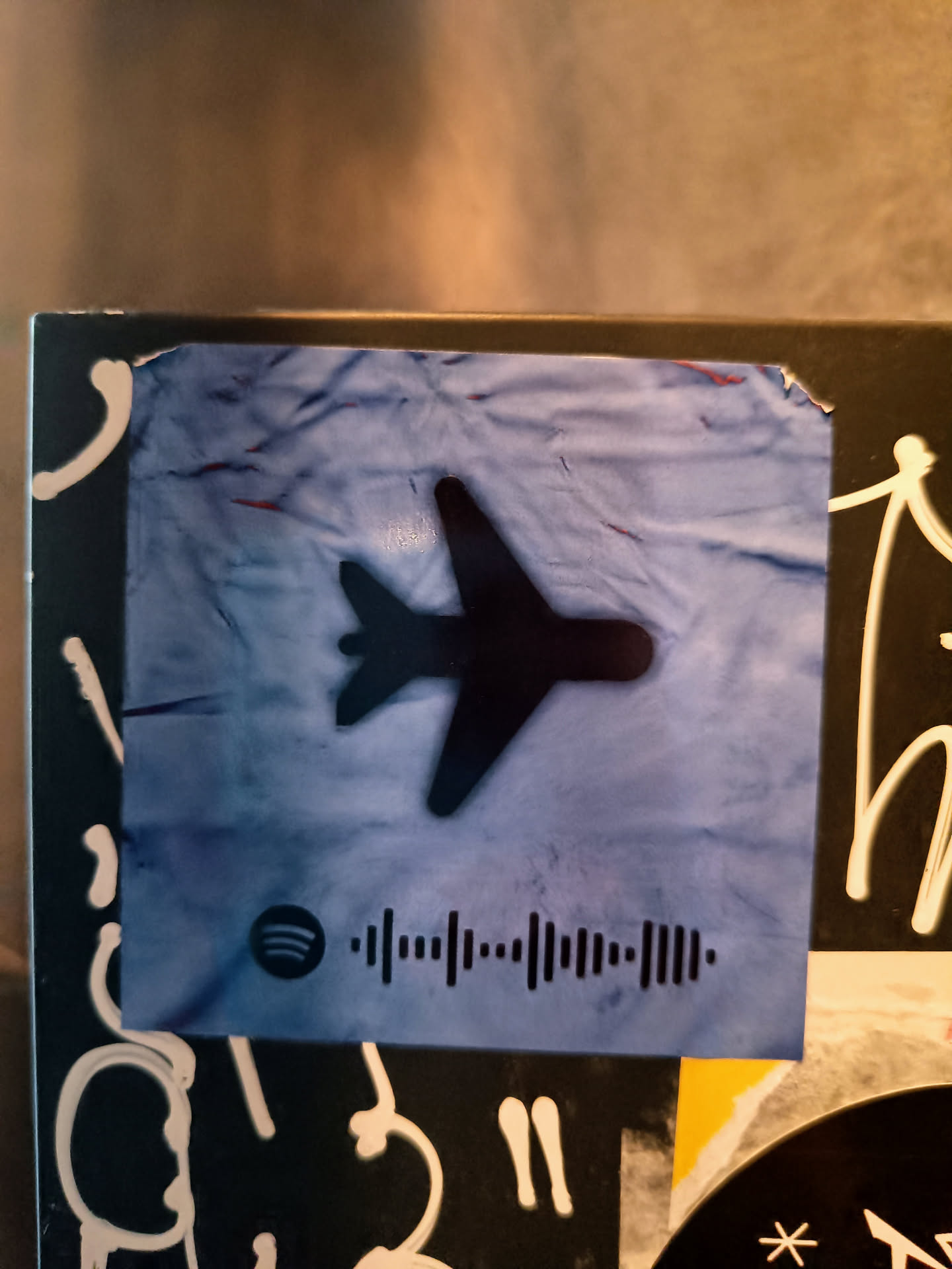 A blue sticker with a plane and a Spotify code.  The Spotify code likely links to a playlist or song related to travel.
