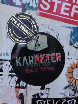 A black round sticker with the text "Karafter Party Box" and the tagline "Bring the Party Home". The year 2016 is also visible on the sticker. Another gold sticker with the text "It's a Present!" is also visible in the image.