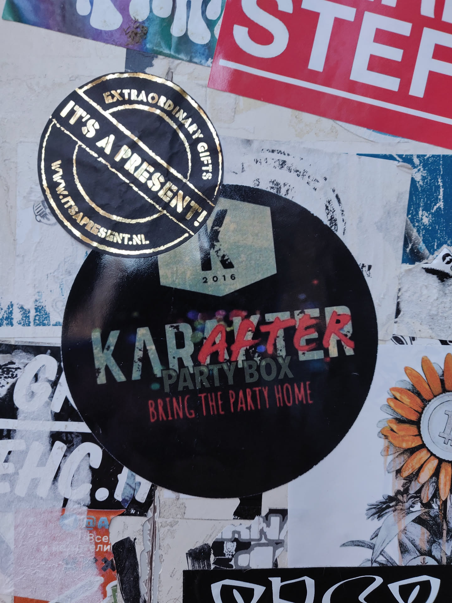 A black round sticker with the text "Karafter Party Box" and the tagline "Bring the Party Home". The year 2016 is also visible on the sticker. Another gold sticker with the text "It's a Present!" is also visible in the image.