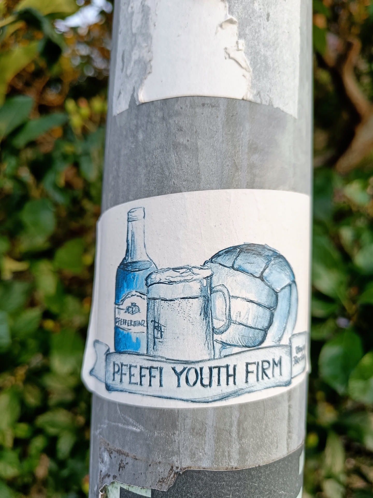 A sticker depicting a bottle of what seems to be Pomerania, a beer mug, and a ball, with the text "PFEFFI YOUTH FIRM" on a banner. The style is hand-drawn, in shades of blue.