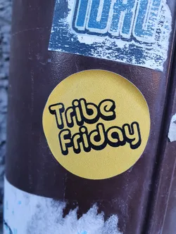 Round yellow sticker with the text "Tribe Friday" in a black retro-style font.
