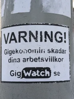 A black and white warning sticker about the gig economy's negative impact on working conditions. It features the text 'WARNING!' in large bold letters, followed by a message in Swedish and the website GigWatch.se.