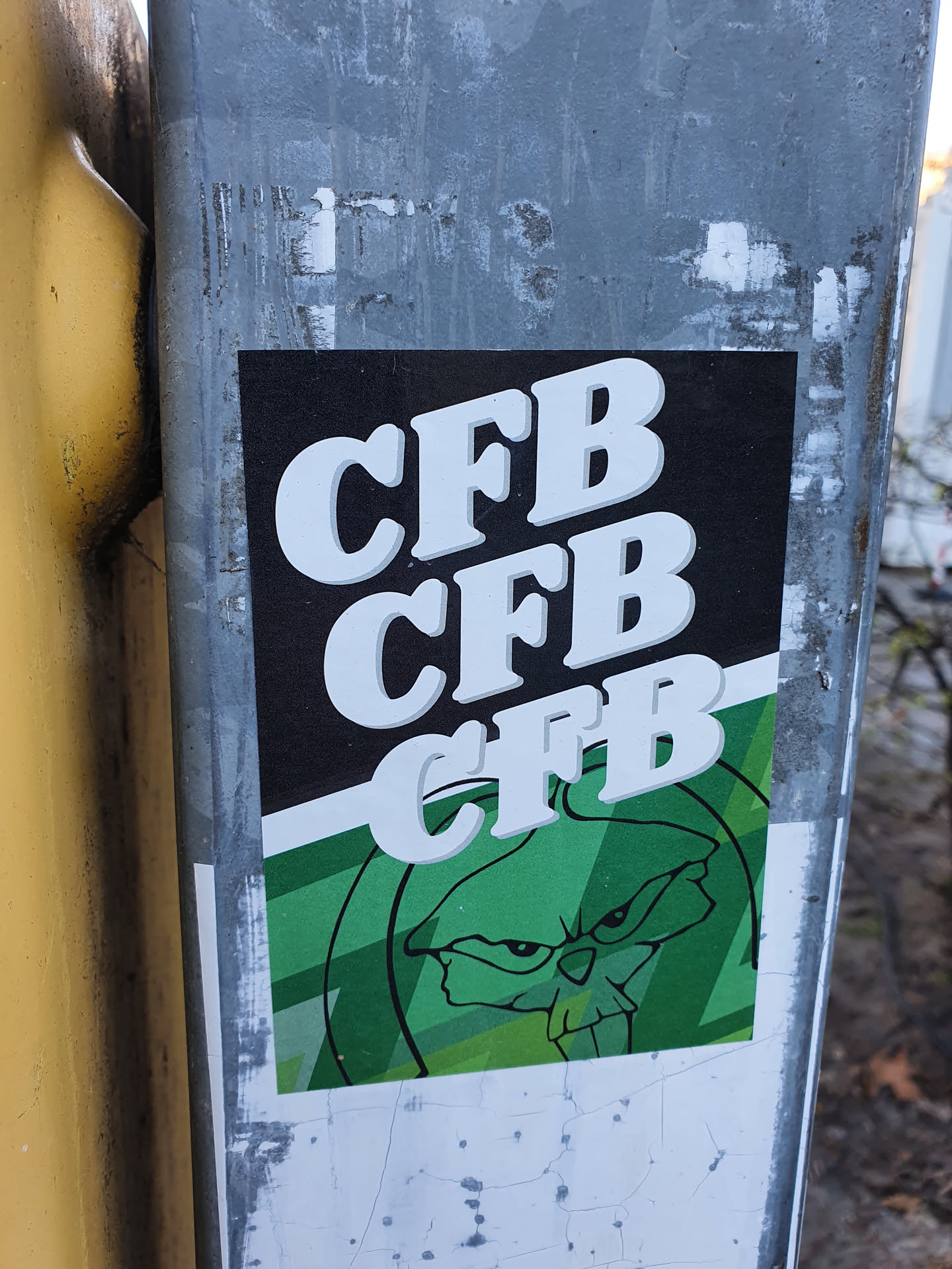 A sticker featuring the acronym "CFB" repeated three times in a retro-style font. Below the text is an illustration of a snarling, green creature with skull-like features. The style is reminiscent of cartoon characters or graffiti art.