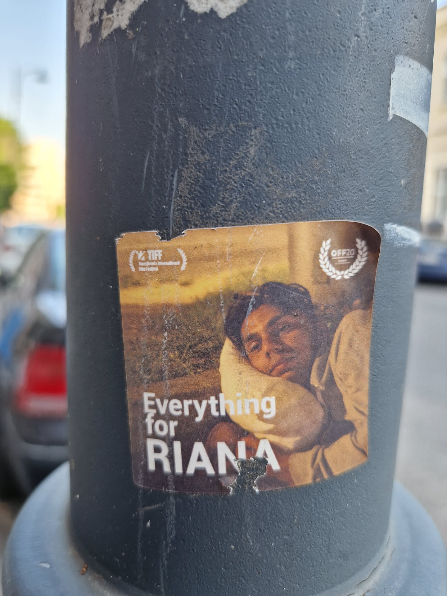 A sticker featuring a person resting their head on their arm. The text 'Everything for RIANA' is prominently displayed.  Logos suggesting film festival participation are visible.