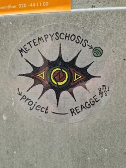 Round sticker featuring an eye with sun rays and the text 'METEMPYSCHOSIS' and 'project _ REAGGE'. A Spotify logo is present on the right side. 
