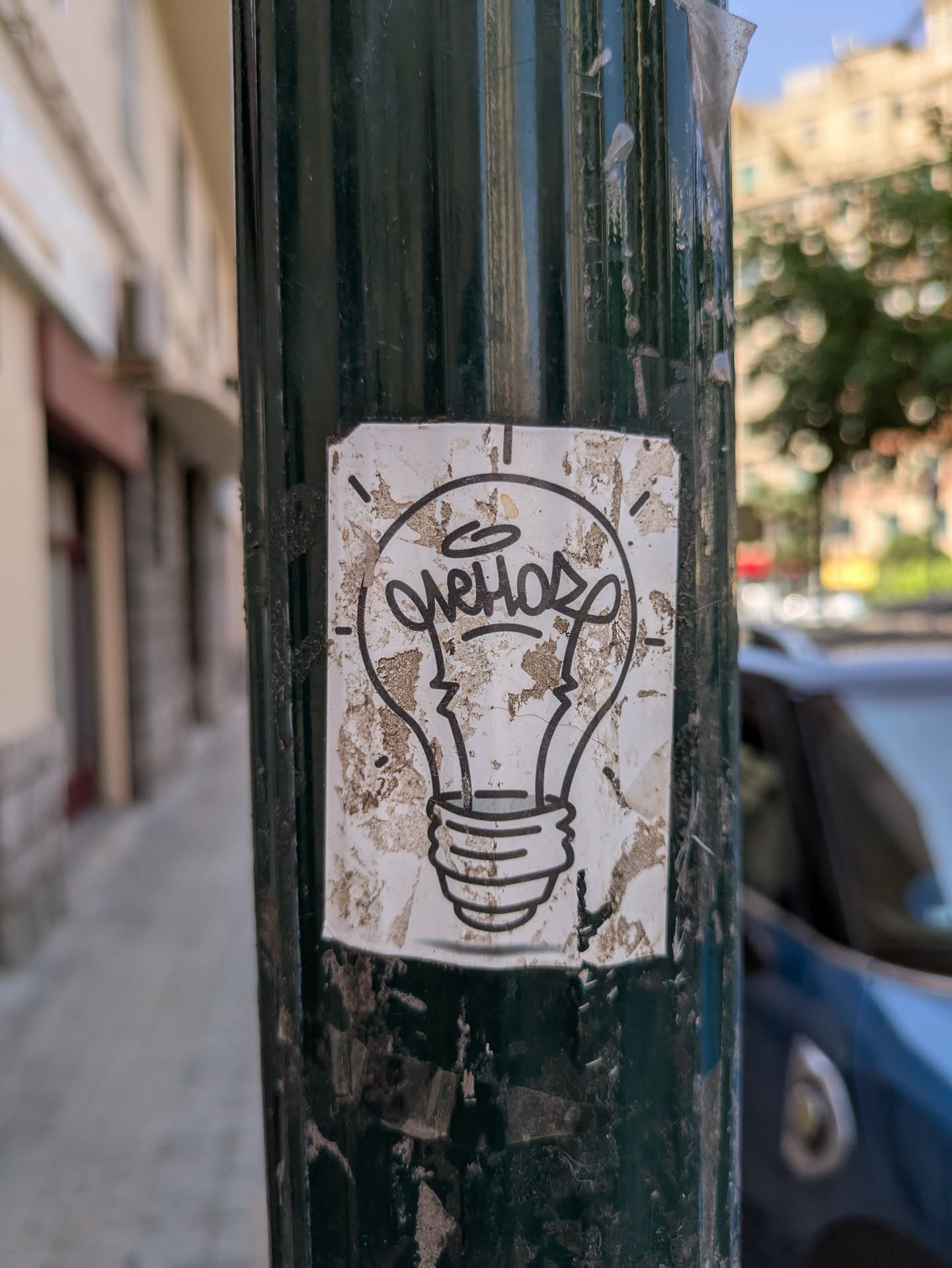 This is a sticker of a simple line art drawing of a light bulb. The sticker has some scratches and tears, and some dirt spots.