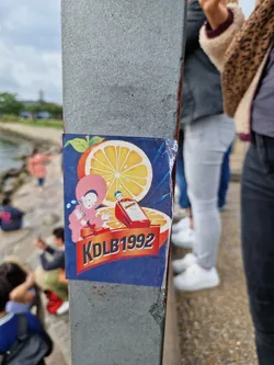 A sticker featuring a cartoon character, a Campari bottle, and oranges. The text 'KDLB1992' is prominently displayed on the sticker.