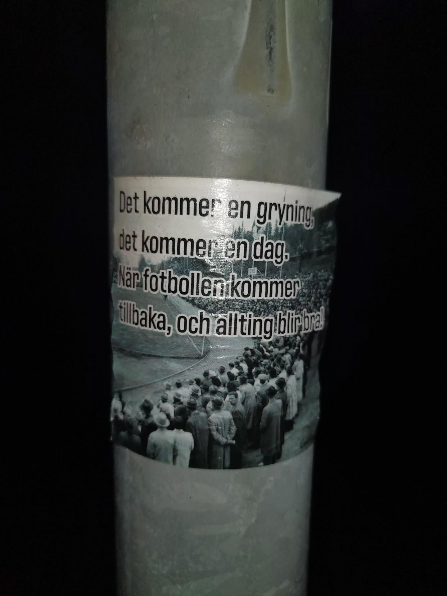 A sticker with a quote in Swedish about the return of football and better times. The sticker features a black and white image of a crowd of people at a stadium.