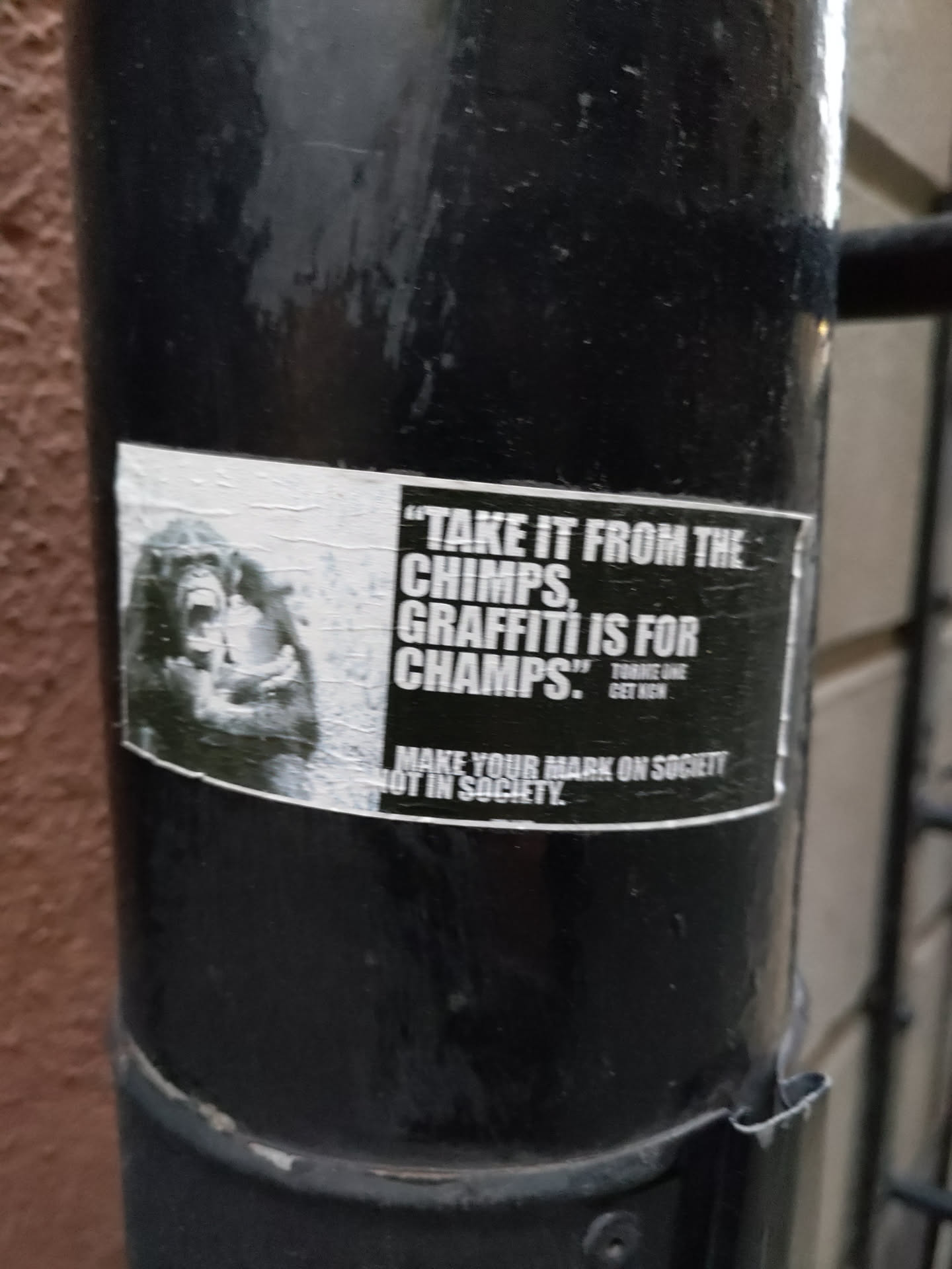A black and white sticker featuring a chimpanzee and a quote about graffiti. The sticker promotes making a mark on society through graffiti.