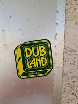 A yellow and green sticker with the text DUB LAND and the website dubland.ro. The design is simple yet effective, and the colors are eye-catching. 