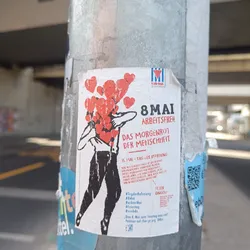 Sticker advocating for May 8th as a public holiday, possibly in Germany, featuring an illustration of a person holding hearts.  The text includes hashtags and mentions a petition.