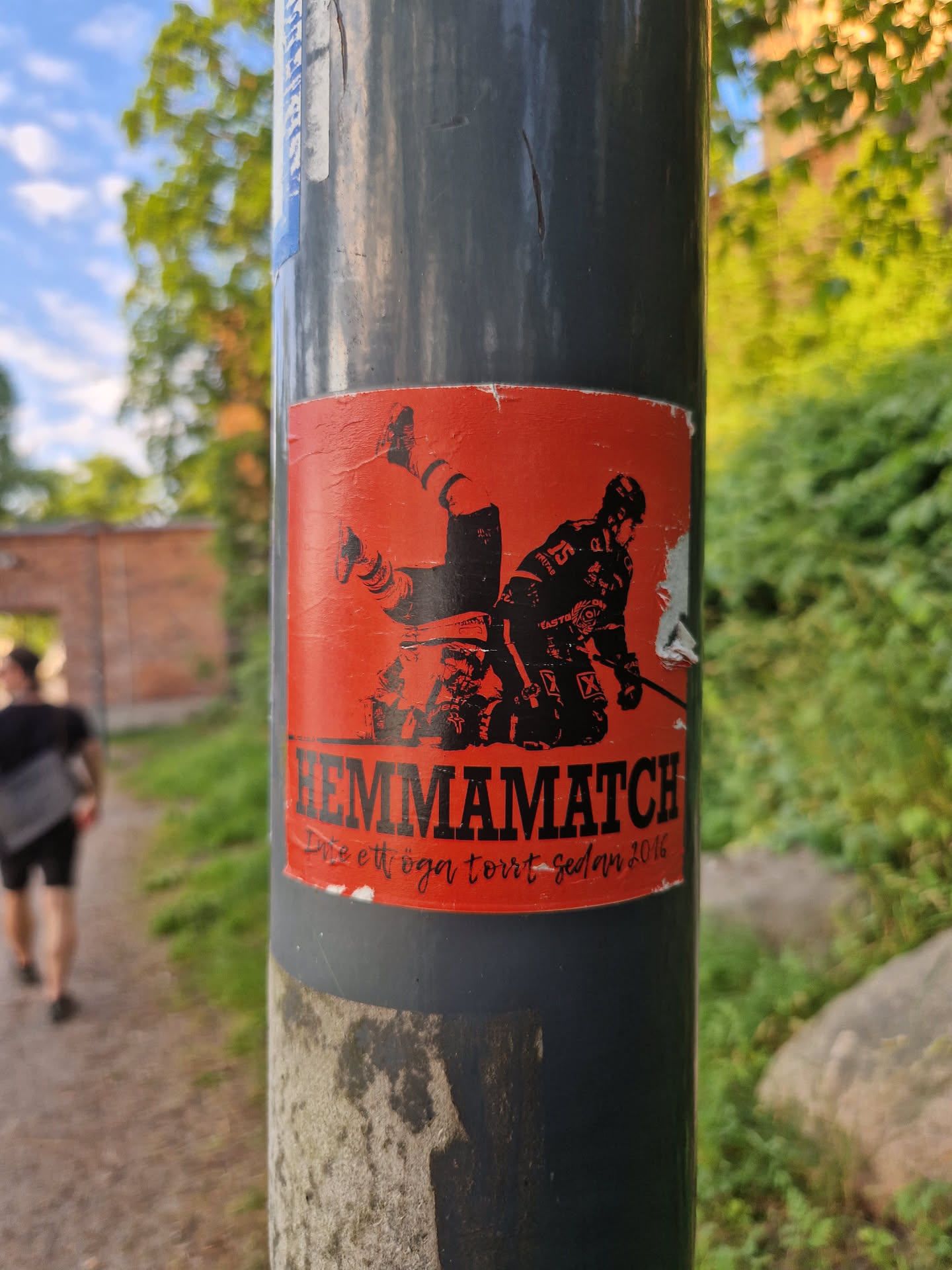 A sticker depicting a hockey player falling down. The text on the sticker says "Hemmamatch - ett eget tört sedan 2016", which translates to "Home match - a home-made cake since 2016".