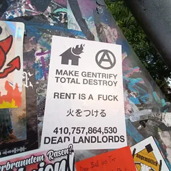 A sticker with an anti-gentrification message. It includes a house with flames, an anarchy symbol, and a large number suggesting a count of landlords.  The text also includes Japanese characters that translate to "set fire".