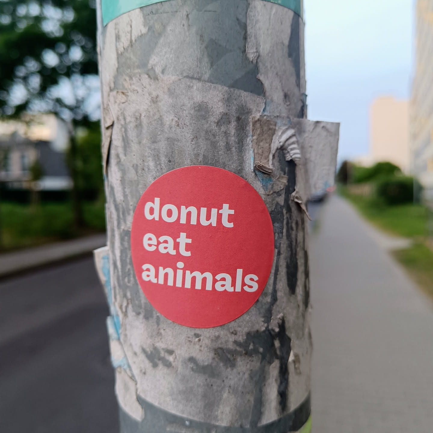 A red circle sticker on a pole with the text "donut eat animals" in white.