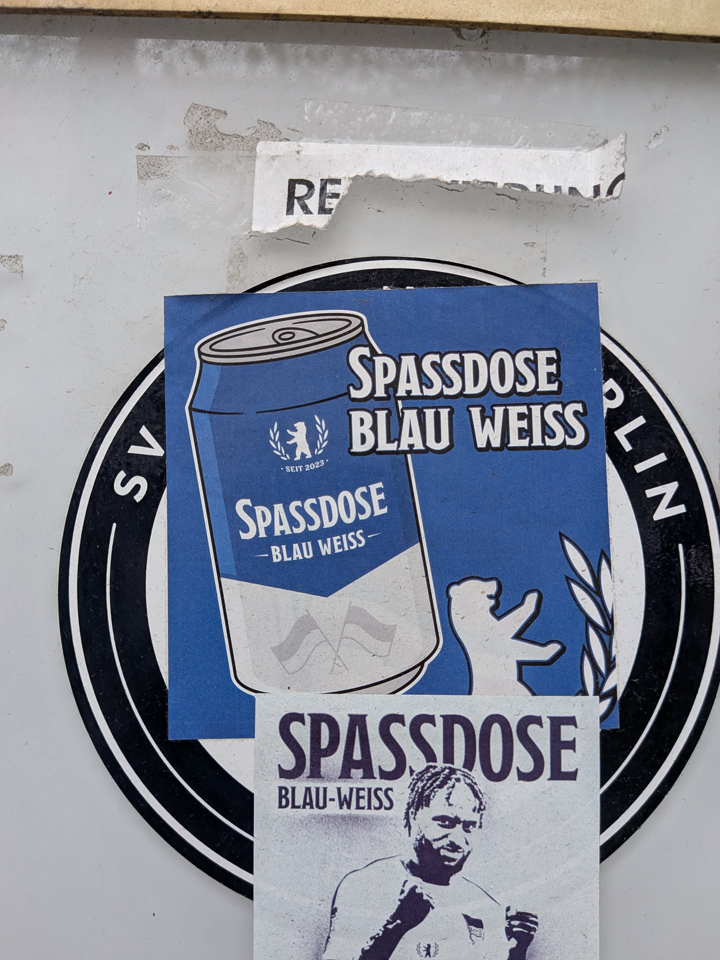 A square sticker predominantly in blue and white, depicting an illustrated beverage can in Hertha BSC club colors (blue and white). The can is labeled 'SPASSDOSE - BLAU WEISS -' and features the Berlin bear inside a wreath with the text 'SEIT 2023'. To the right of the can, the phrase 'SPASSDOSE BLAU WEISS' is printed in bold white font with black outlines. A silhouette of the Berlin bear is visible in the lower right corner next to a laurel branch.