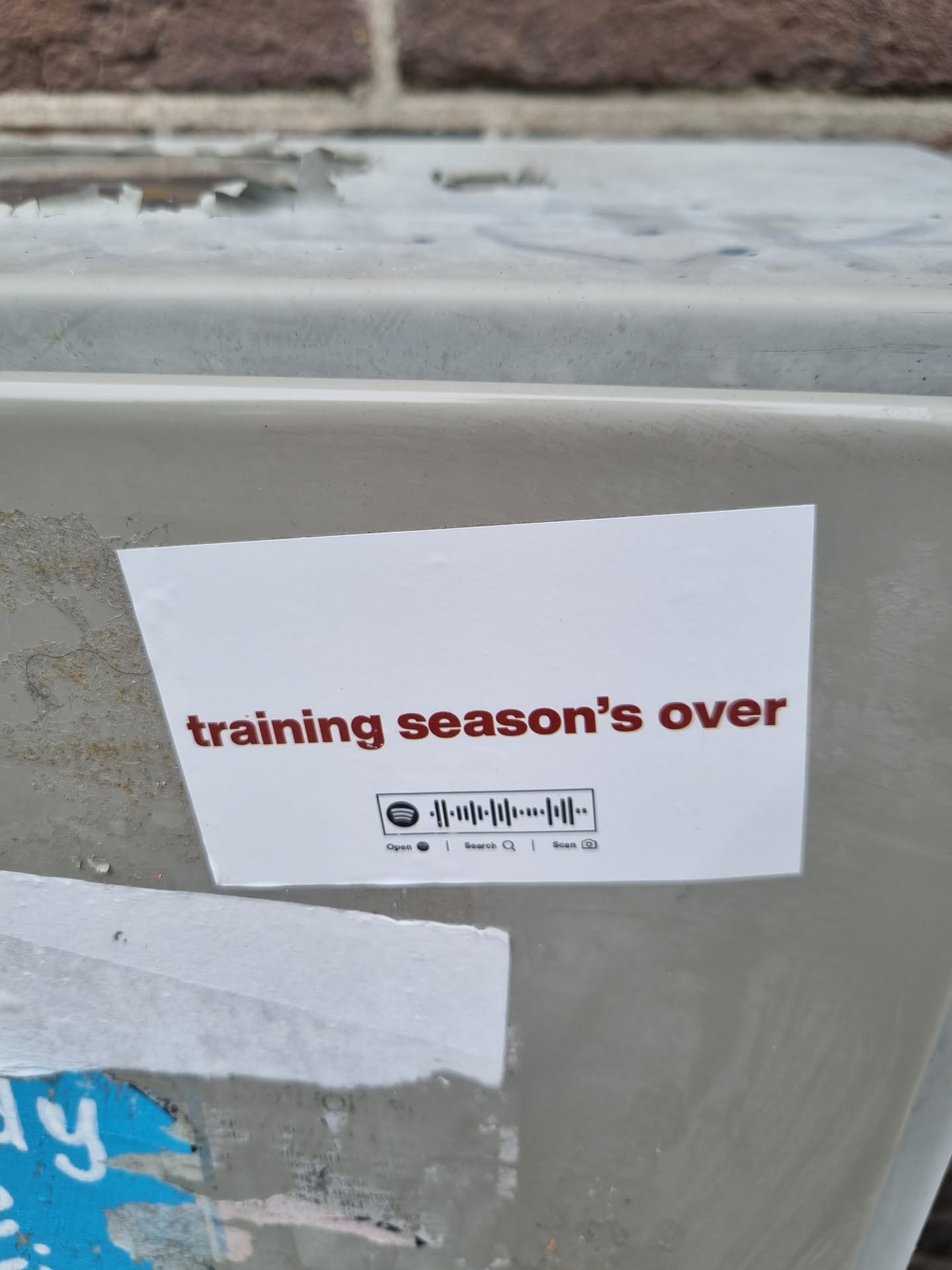 A white sticker with the text "training season's over" in dark red.  It also contains a Spotify code.