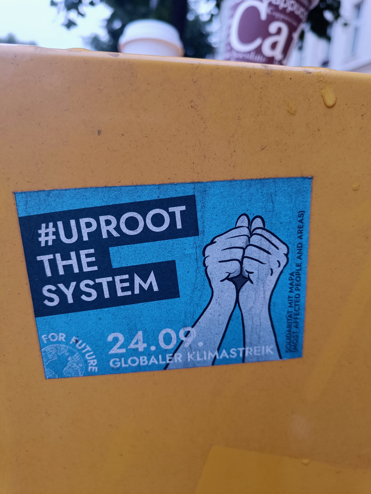A sticker advocating for climate action with the text '#Uproot The System', '24.09. Globaler Klimastreik', and 'For Future'. It features two hands clasped together, symbolizing unity and action.