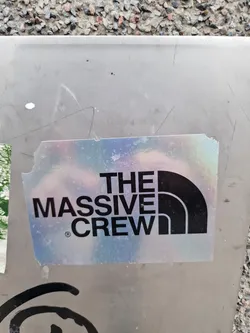 A holographic sticker with the text "THE MASSIVE CREW" and a logo resembling the North Face logo. The sticker is slightly damaged at the edges.
