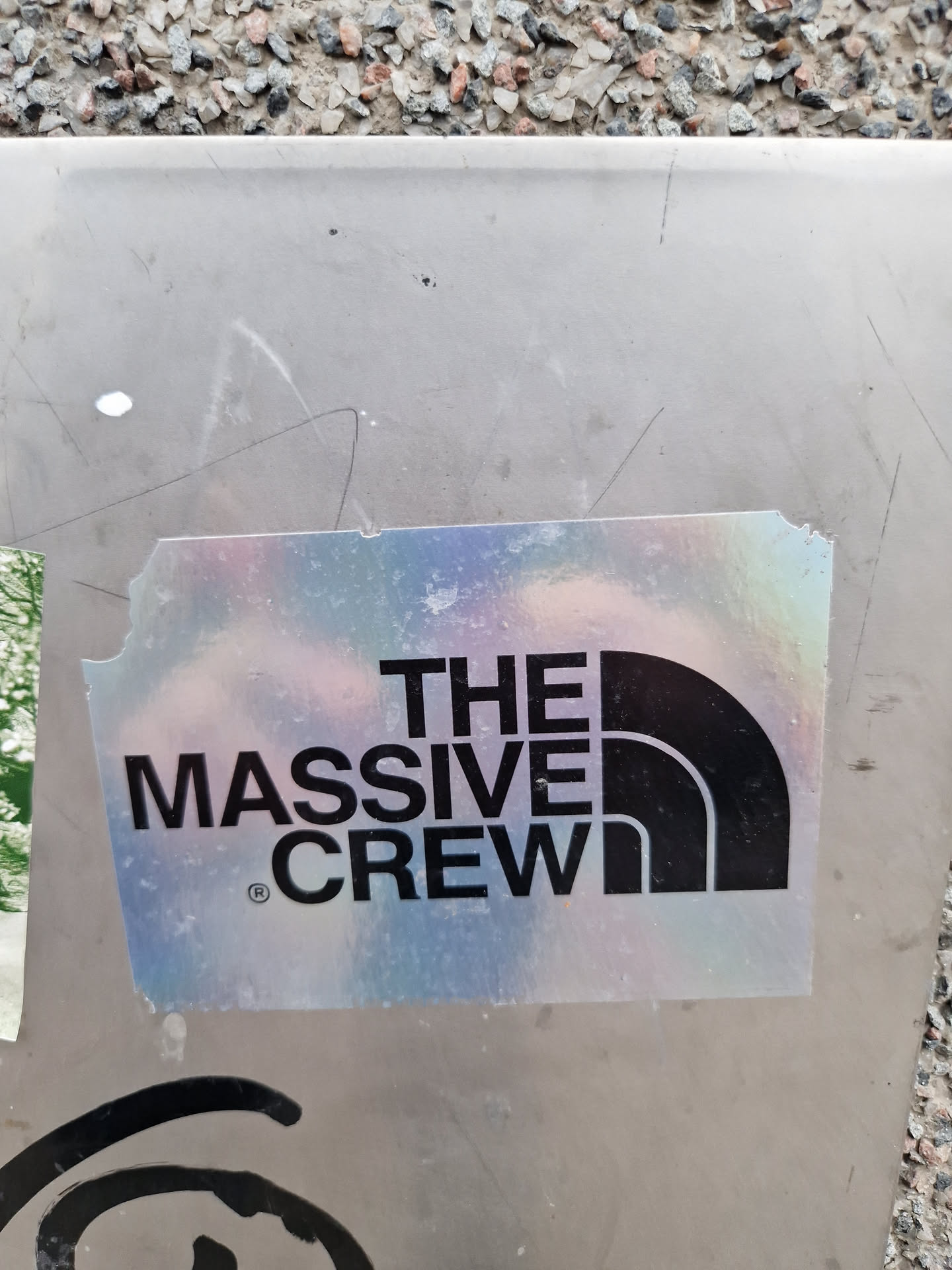A holographic sticker with the text "THE MASSIVE CREW" and a logo resembling the North Face logo. The sticker is slightly damaged at the edges.