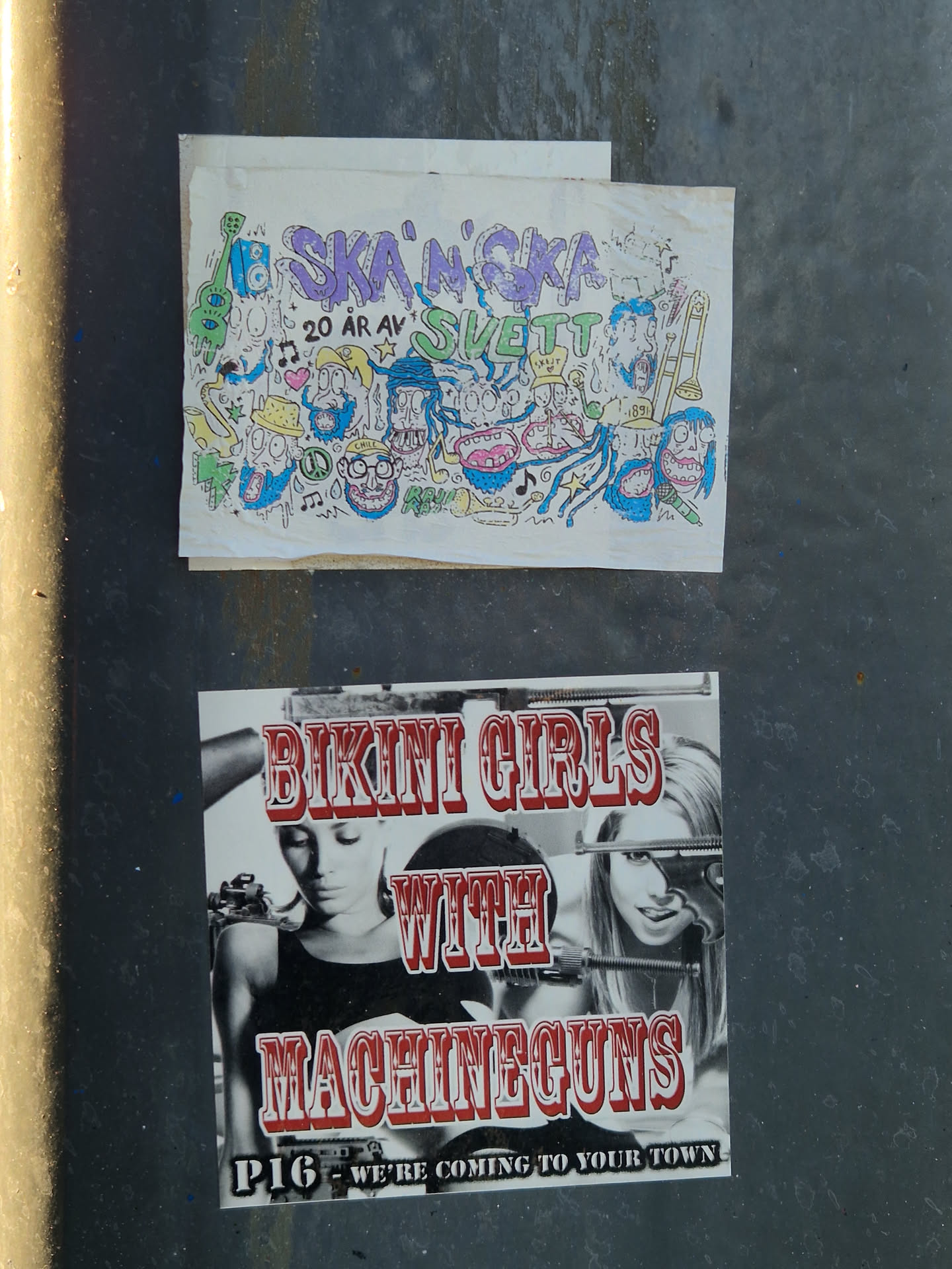The sticker is a black and white image with prominent red text overlay. It depicts two women; the left one is shown in a partial profile, looking downwards, while the right one is shown from the chest up, looking directly at the viewer with a slight smile, with what appears to be a stylized machine gun near her face. The title 'BIKINI GIRLS WITH MACHINEGUNS' is in large, embossed-looking red letters, dominating the top half of the design. Below the women, in smaller white text with a black outline, is 'P1G - WE'RE COMING TO YOUR TOWN', suggesting a band name and a tour or presence. The overall aesthetic hints at a grindhouse movie poster or punk/rock band imagery.