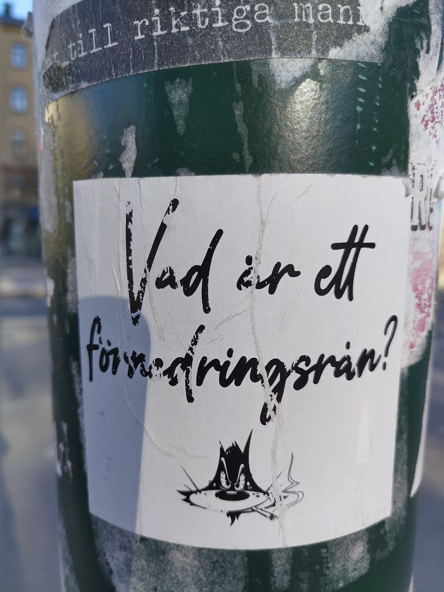 A sticker with a question in Swedish: "Vad är ett försäkringsbrån?" (What is an insurance fraud?). It features a cartoon drawing of a cat smoking a cigarette.
