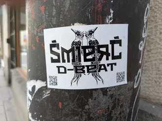 The sticker features two woodpeckers facing each other above the text "ŚMIERĆ D-BEAT". The text is in a bold, blocky font. There are QR codes on the bottom left and right corners of the sticker.