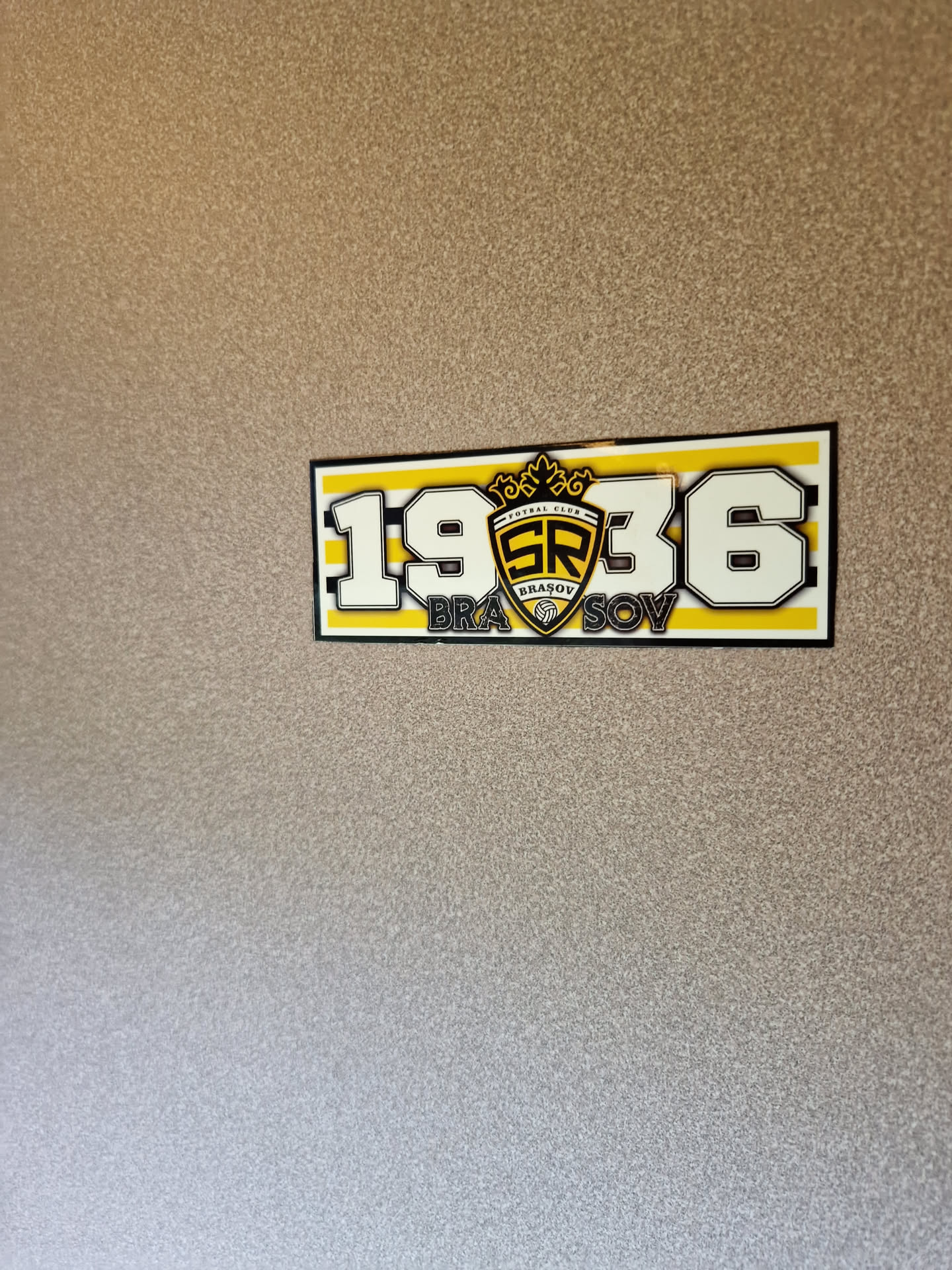 A sticker featuring the text "1936" with the words "Brasov" underneath, and a logo in the center. The design uses yellow and black colors.