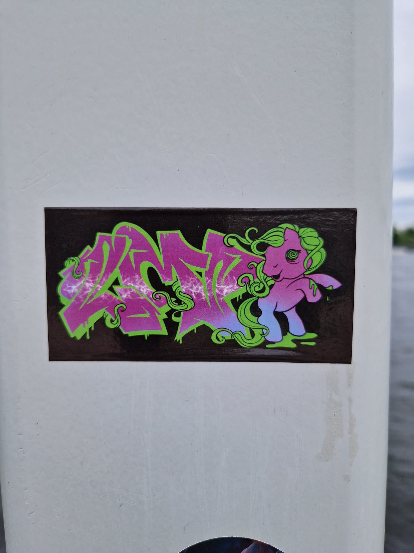 A sticker featuring a My Little Pony character incorporated into a graffiti-style design. The pony is pink and purple with green hair, set against a backdrop of vibrant graffiti lettering.