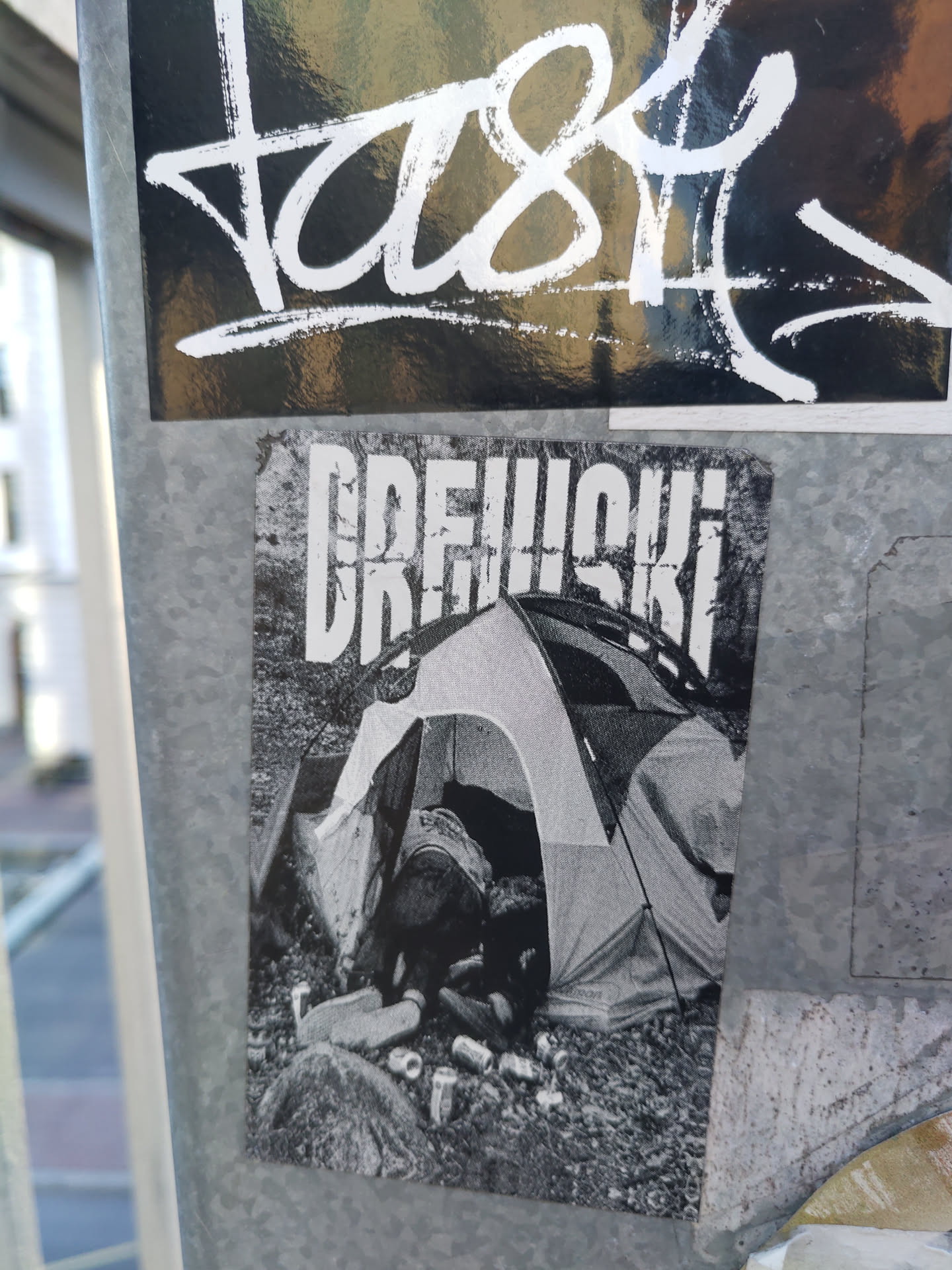 Black and white sticker depicting a person sleeping in a tent surrounded by empty cans. The word DREWSKI is prominently displayed at the top.