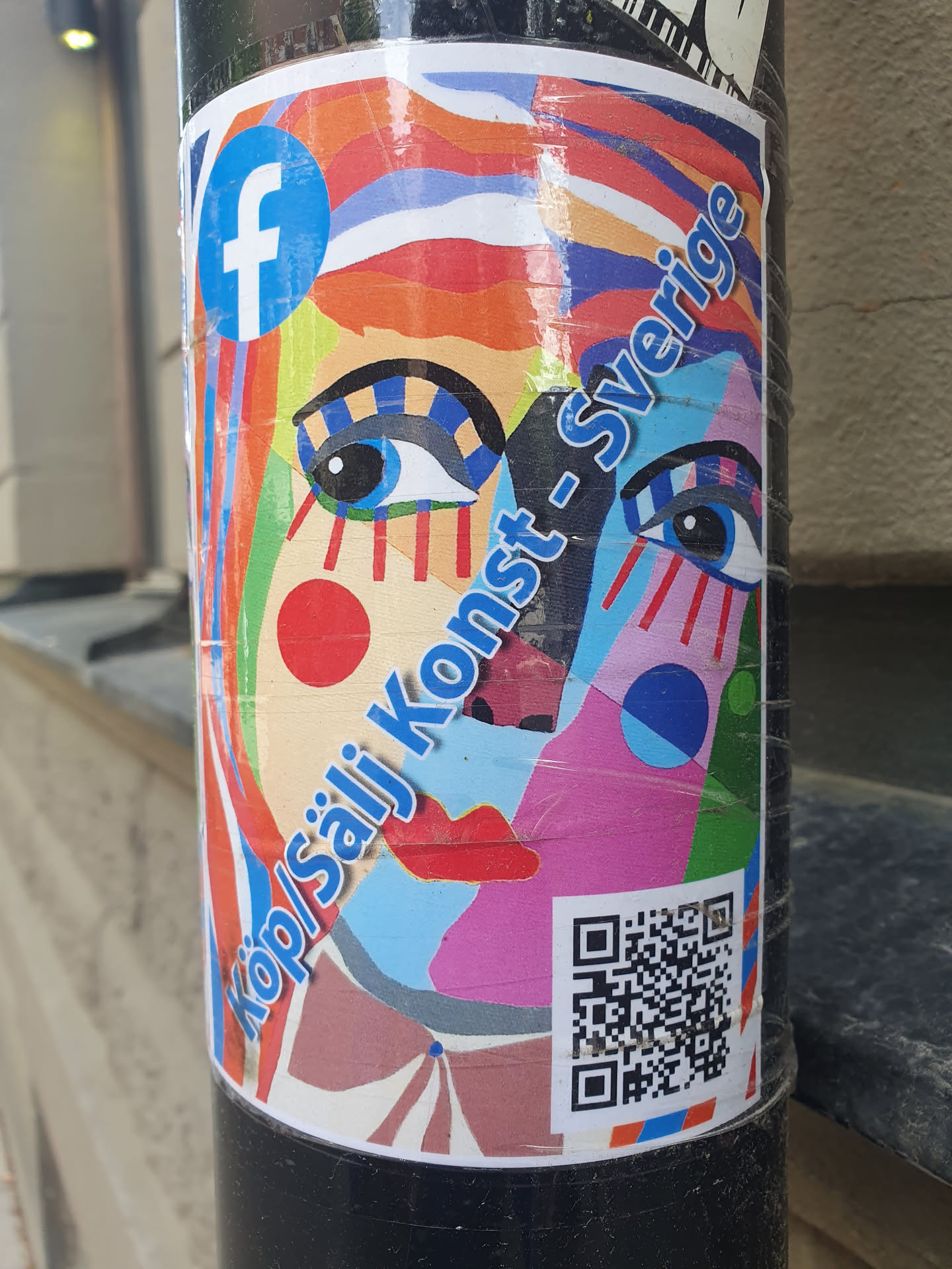 A colorful sticker featuring an abstract face design with text that reads "Köp/Sälj Konst-Sverige" and a Facebook logo.  There is a QR code present on the sticker.