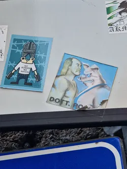 A sticker depicting a stylized image of Hulk Hogan facing off against an aggressive pig. The style is reminiscent of punk rock or alternative art.  The sticker has some text at the bottom that says "DOTT. ROCK".