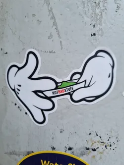A sticker depicting two Mickey Mouse-like hands rolling what appears to be a marijuana joint. The text 'NOTBADSTUFF' is written across the joint.