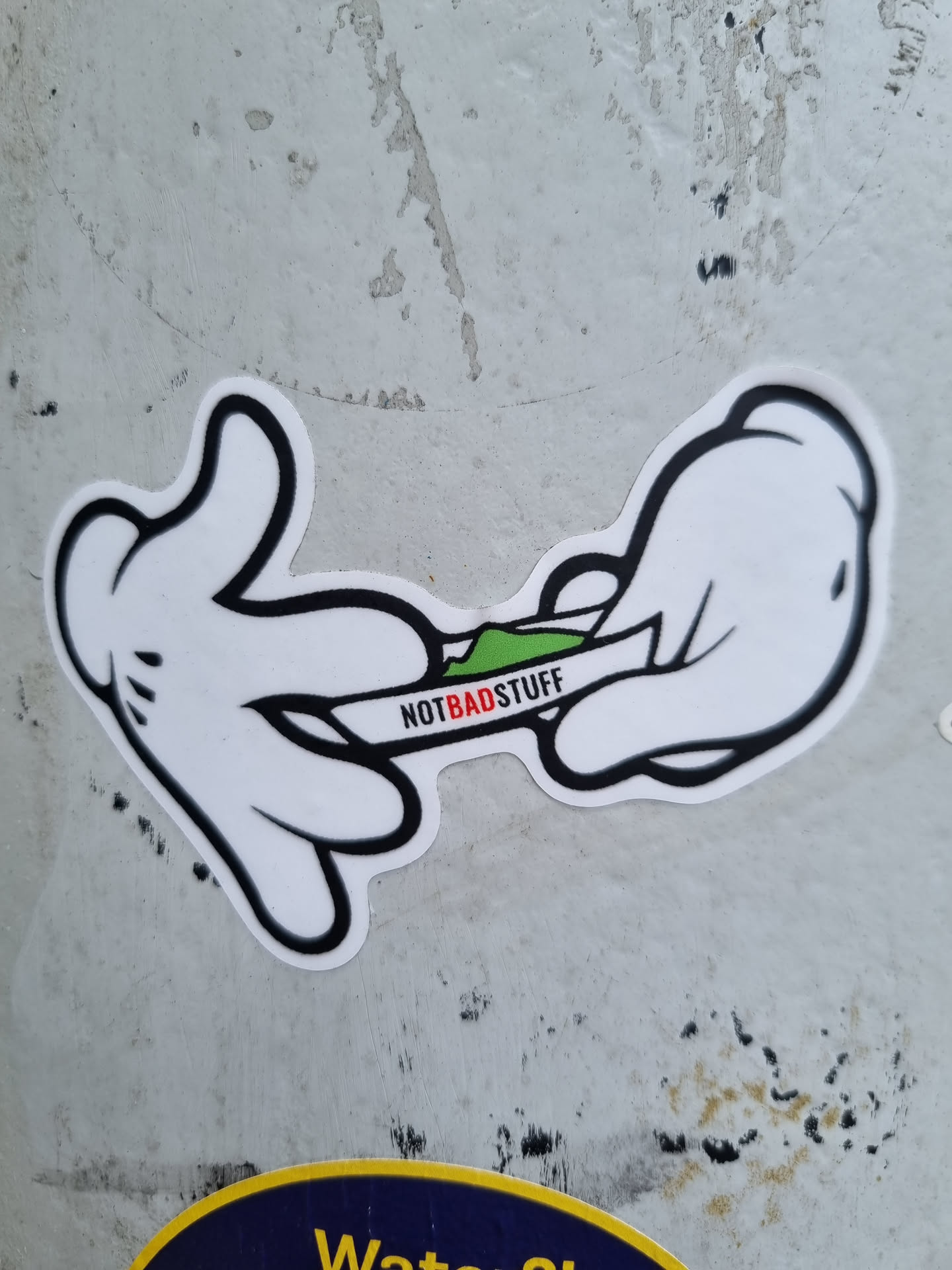 A sticker depicting two Mickey Mouse-like hands rolling what appears to be a marijuana joint. The text 'NOTBADSTUFF' is written across the joint.
