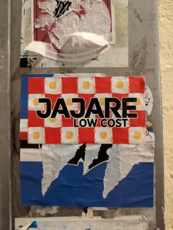 The sticker features a red and white checkered pattern with fried eggs. The text "JAJARE" is written in black bold letters across the center, and "LOW COST" is written below it.